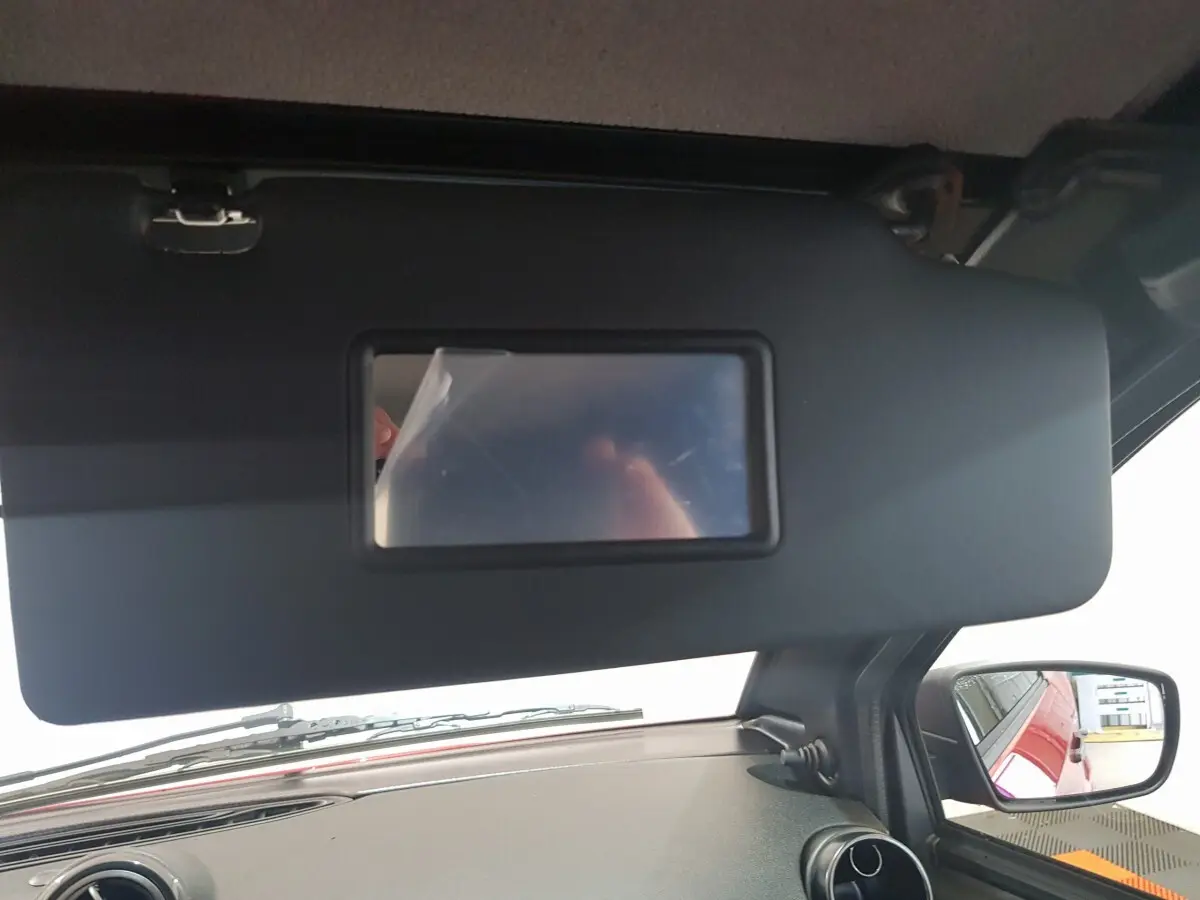 Vue intérieure côté conducteur de l'AIXAM Ambition rouge 2026, avec pare-soleil et rétroviseur extérieur caméra visible.