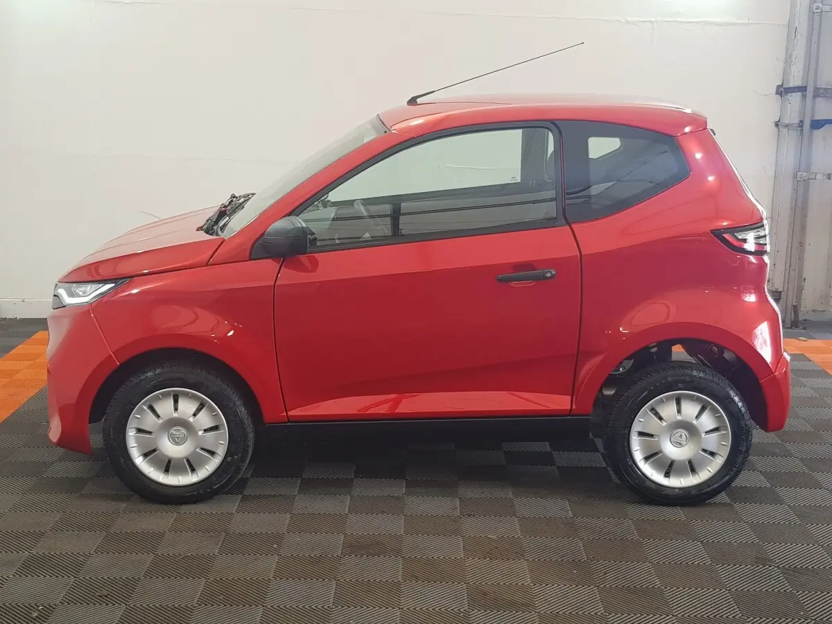 Vue de profil côté gauche d'une Aixam Ambition 0.5 City Pack rouge, compacte avec rétroviseur caméra côté conducteur.