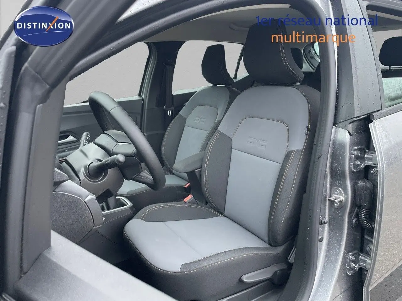 Vue intérieure côté conducteur de la Dacia Sandero Stepway 2024, sièges gris clair et foncé avec surpiqûres contrastées.