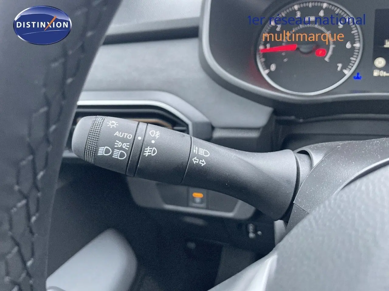 Gros plan sur la commande des phares et clignotants du tableau de bord d'une Dacia Sandero Stepway gris schiste 2024.