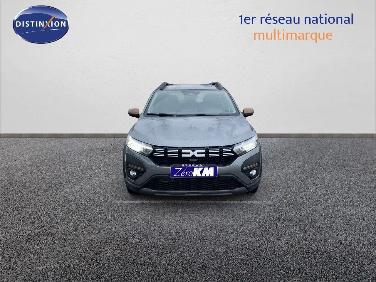 Vue frontale d'une Dacia Sandero Stepway 2024 gris schiste métal avec calandre noire et rétroviseurs bronze.