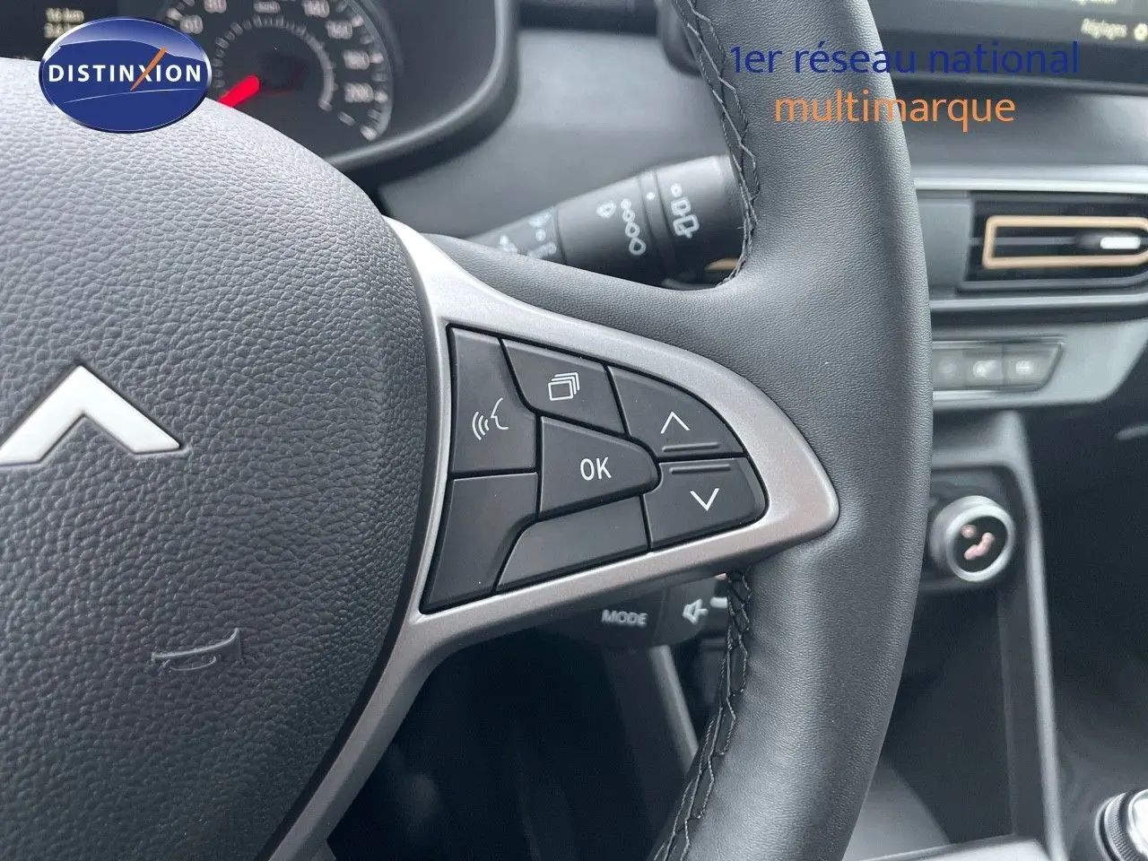 Gros plan sur le volant noir de la Dacia Sandero Stepway 2024, montrant les commandes multifonctions côté droit.