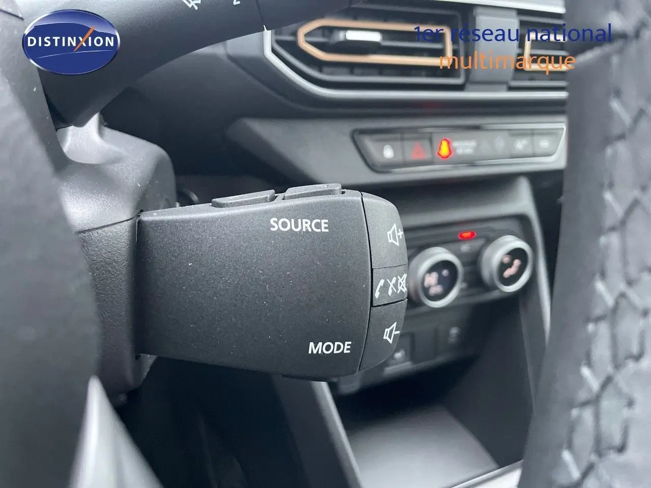 Commande au volant avec boutons source et mode, tableau de bord et commandes de climatisation du Dacia Sandero Stepway 2024.