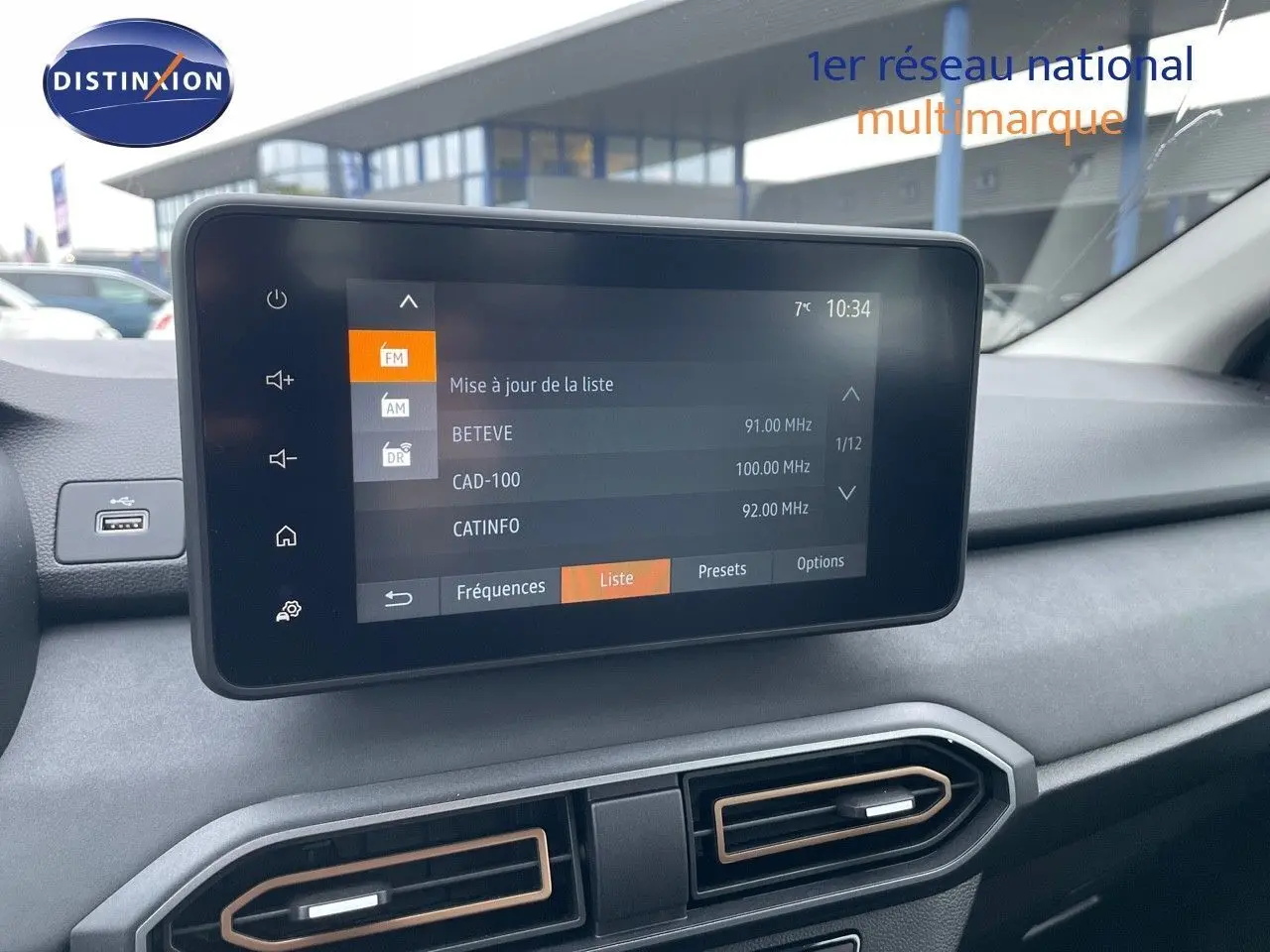 Écran tactile central affichant la liste des stations radio dans l'habitacle gris d'une Dacia Sandero Stepway 2024.