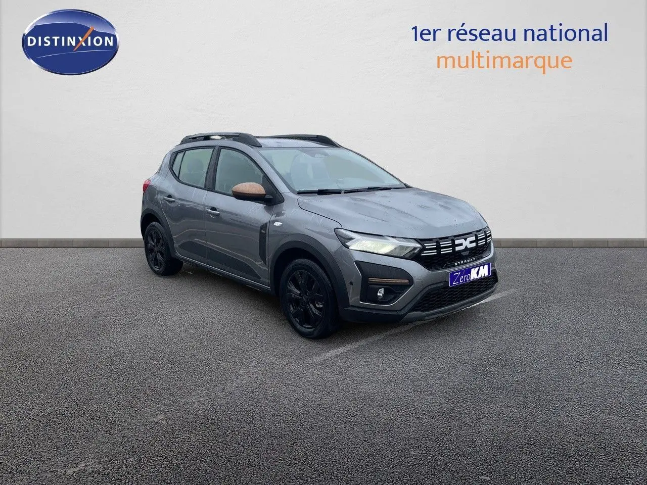 Vue 3/4 avant droite d'une Dacia Sandero Stepway gris schiste métal avec rétroviseurs bronze et jantes noires.