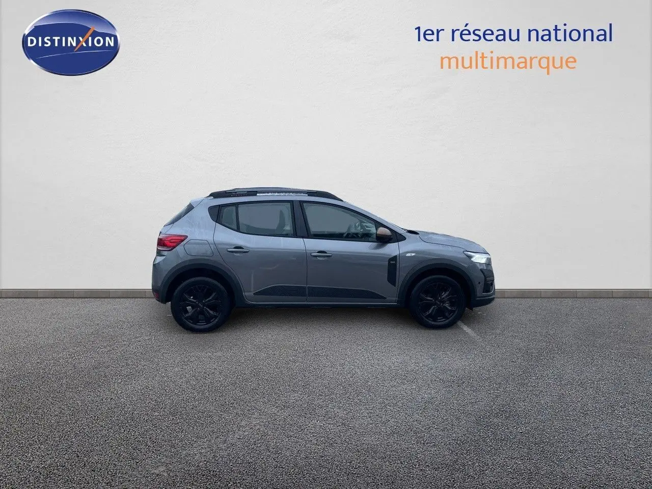 Profil côté gauche d'une Dacia Sandero Stepway 2024 gris schiste métal avec jantes noires et rétroviseurs bronze.