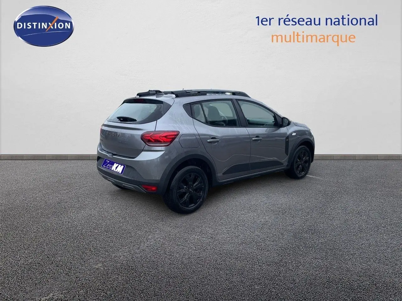 Vue 3/4 arrière droite d'une Dacia Sandero Stepway 2024 gris schiste métal avec jantes noires et toit noir.