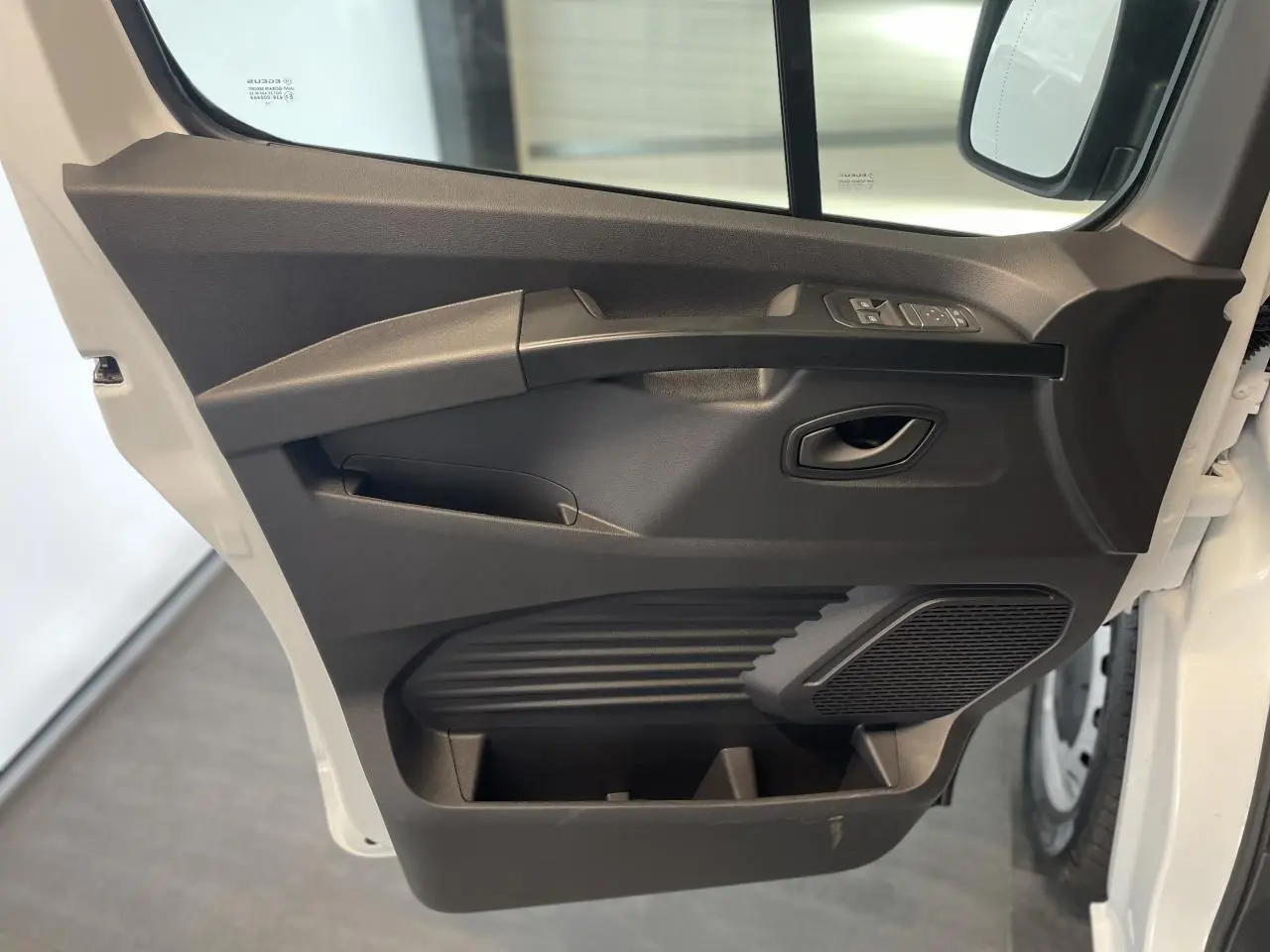 Porte côté conducteur ouverte du Renault Trafic Fourgon blanc, montrant les commandes de vitre et le haut-parleur intégré.