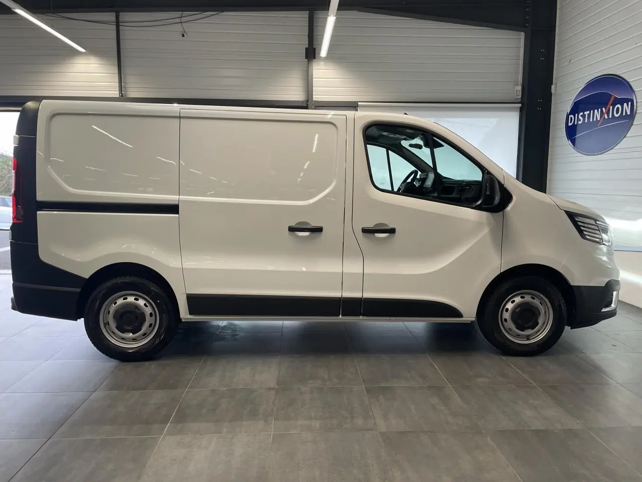 Profil droit du Renault Trafic Fourgon blanc Glacier L1H1, avec jantes tôles 16 pouces et poignées noires.