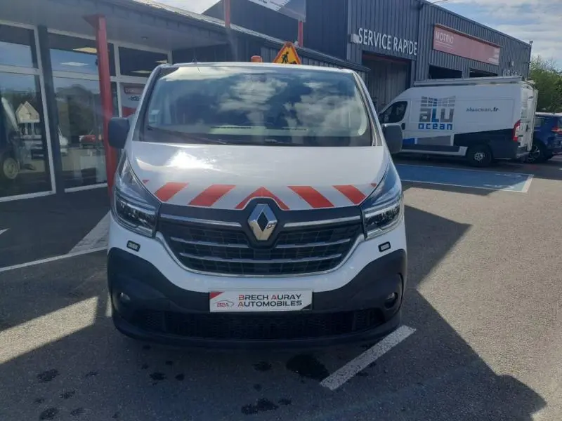 Vue frontale d'un Renault Trafic Fourgon blanc glacier avec bandes rouges diagonales sur le capot et calandre noire.