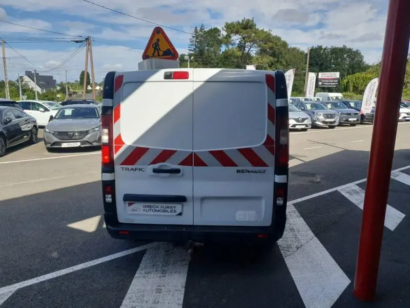 Vue arrière d'un Renault Trafic Fourgon blanc glacier avec bandes réfléchissantes rouges et blanches sur les portes arrière.