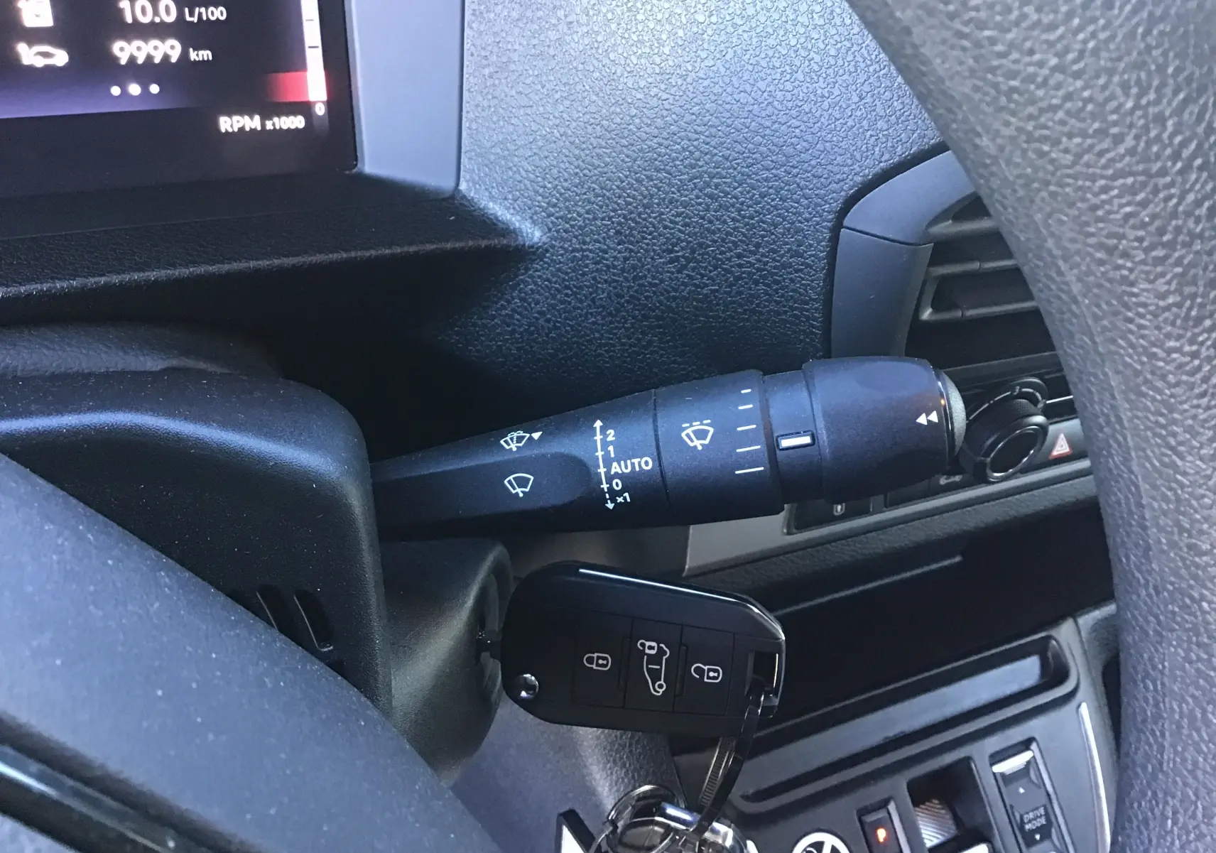 Gros plan sur la clé insérée dans le contacteur et le commodo d'essuie-glace du tableau de bord du Fiat Scudo Fourgon blanc.