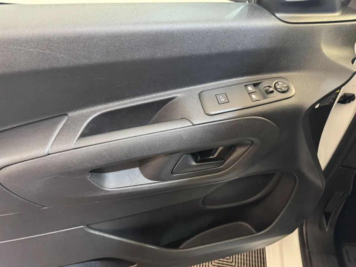 Vue intérieure côté conducteur de la porte noire du Citroën Berlingo blanc, avec commandes électriques des vitres et rétroviseurs.