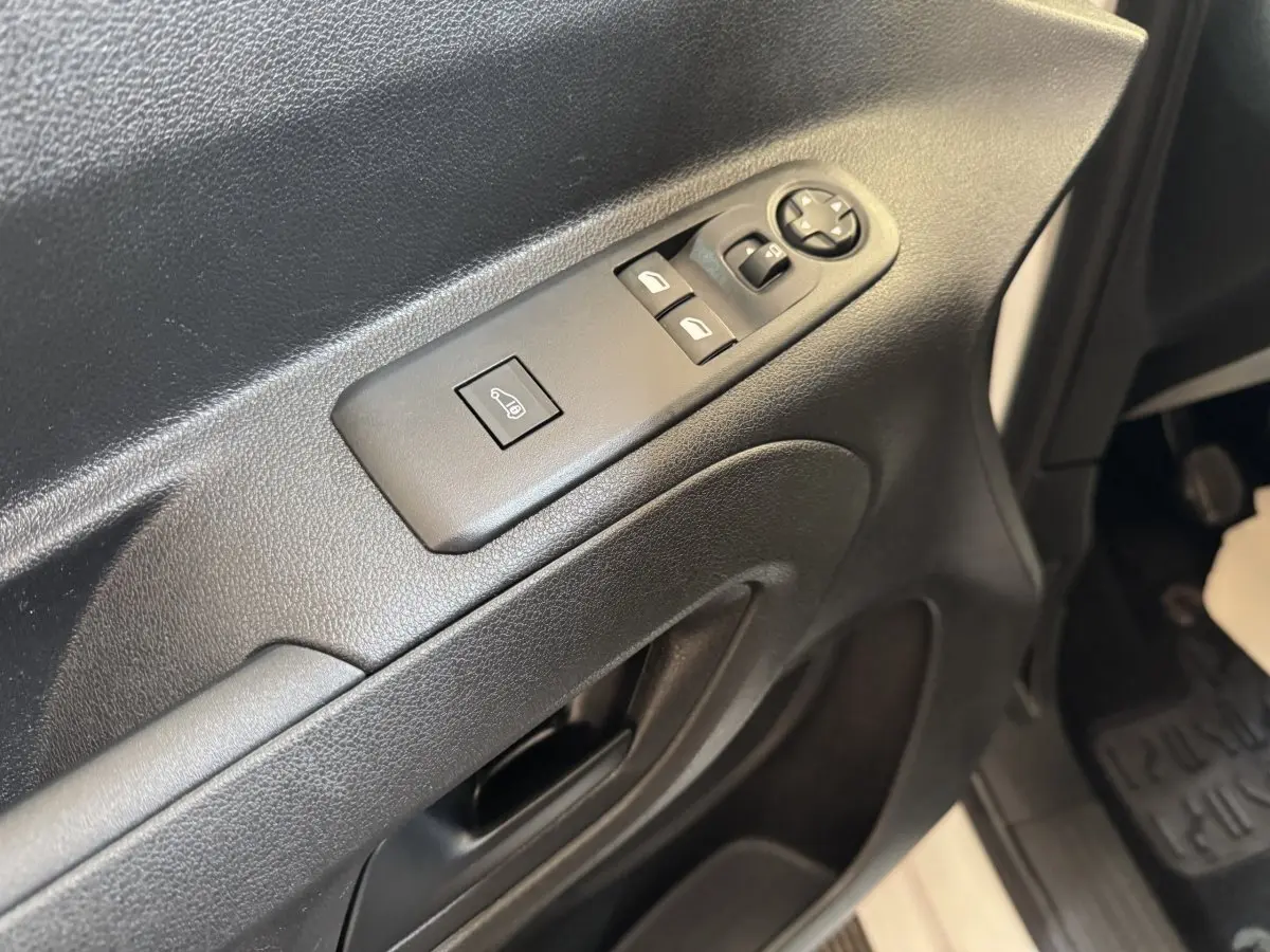 Détail de la porte côté conducteur du Citroën Berlingo blanc, montrant les commandes électriques des vitres et rétroviseurs.