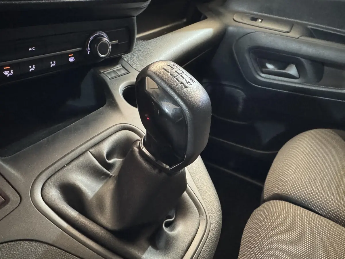Gros plan sur le levier de vitesses manuel noir dans l’habitacle sombre du Citroën Berlingo blanc de 2020.