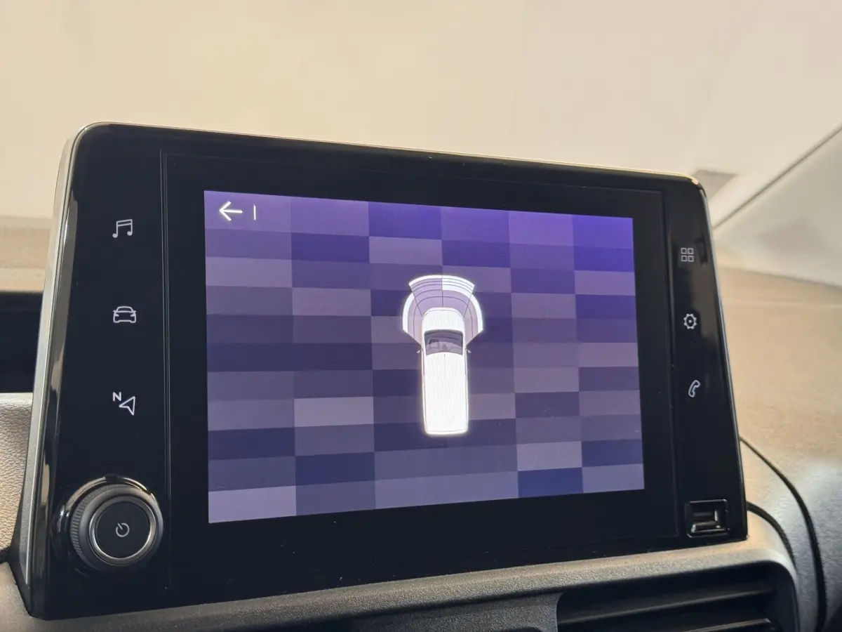 Écran tactile central affichant l'aide au stationnement du Citroën Berlingo blanc, vue intérieure du tableau de bord.