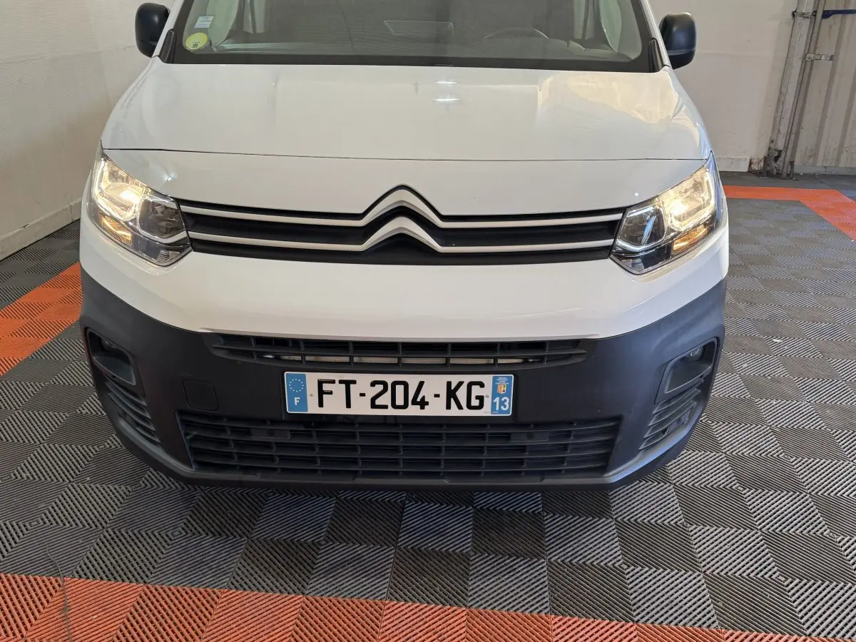 Vue frontale d'un Citroën Berlingo blanc 2020 avec phares allumés et pare-chocs noir mat visible.