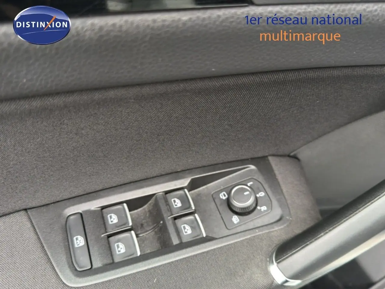 Gros plan sur les commandes des vitres électriques et réglage des rétroviseurs côté conducteur d’un Volkswagen Touran blanc.