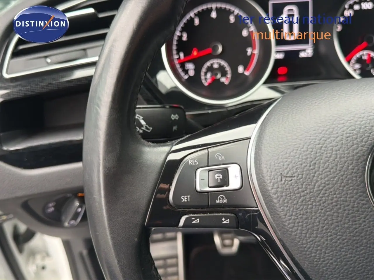 Gros plan sur le volant noir du Volkswagen Touran blanc 2018, montrant les commandes de régulateur de vitesse.