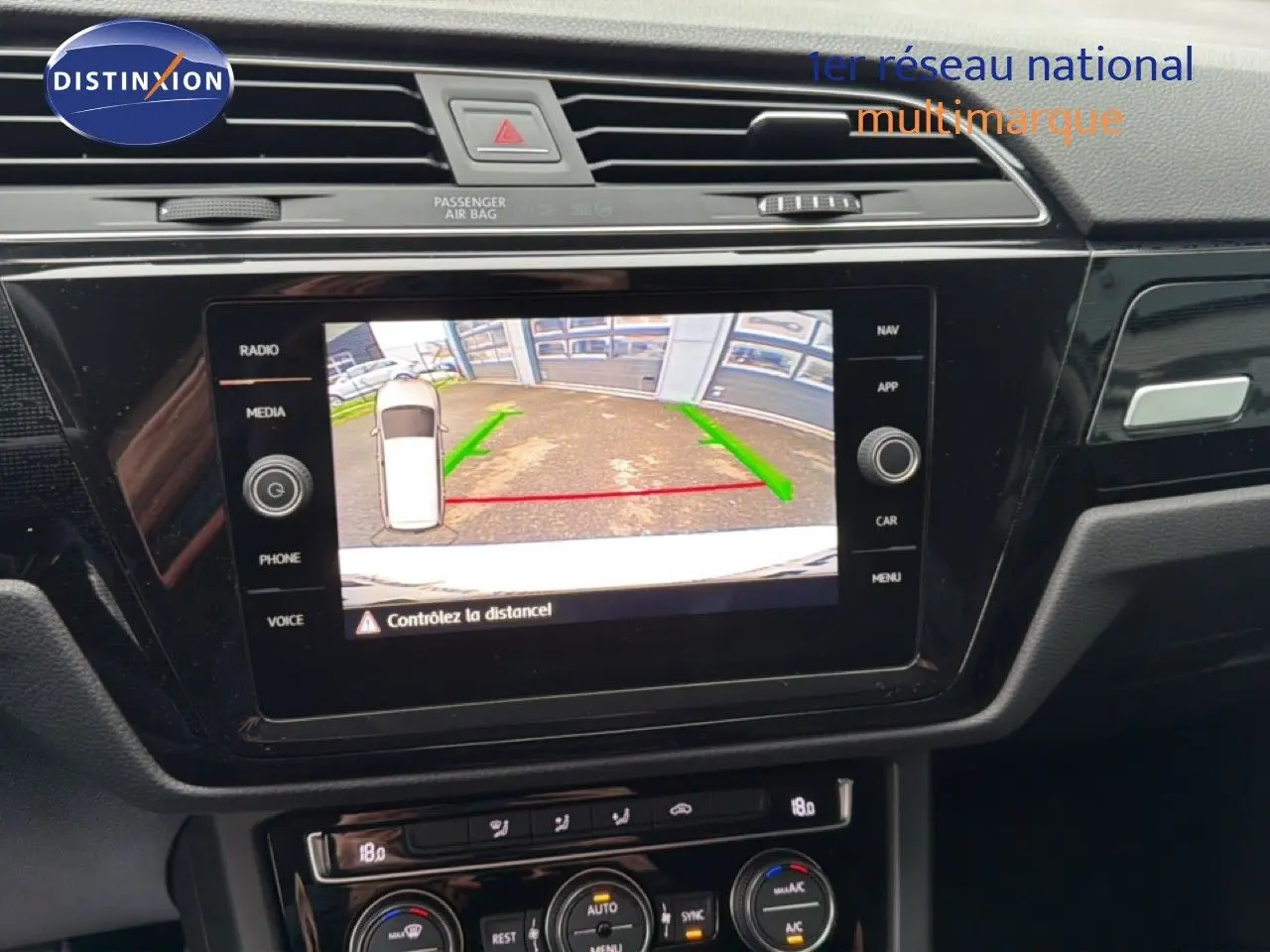 Écran central affichant la caméra de recul du Volkswagen Touran blanc, vue intérieure du tableau de bord.