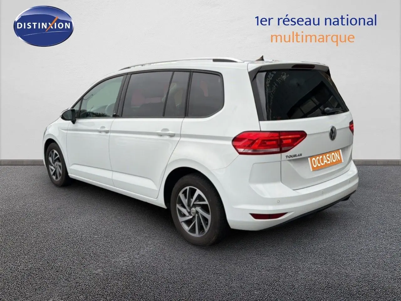 Vue 3/4 arrière droite d'un Volkswagen Touran blanc de 2018 avec feux arrière LED et jantes alliage bicolores.