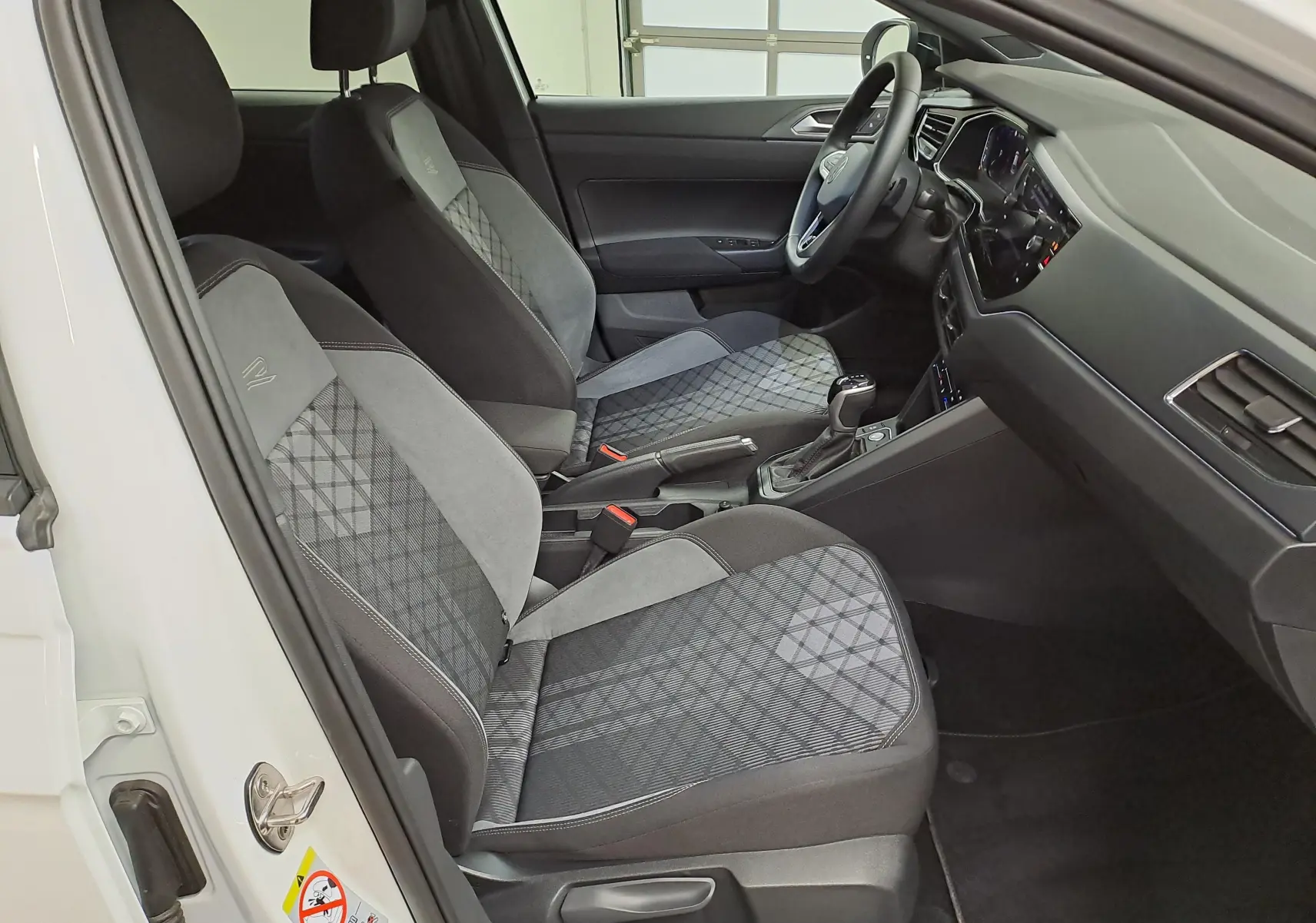Vue intérieure côté gauche du Volkswagen Taigo 1.5 TSI 150 DSG7 R-Line Edition avec sièges tissu gris à motifs géométriques.