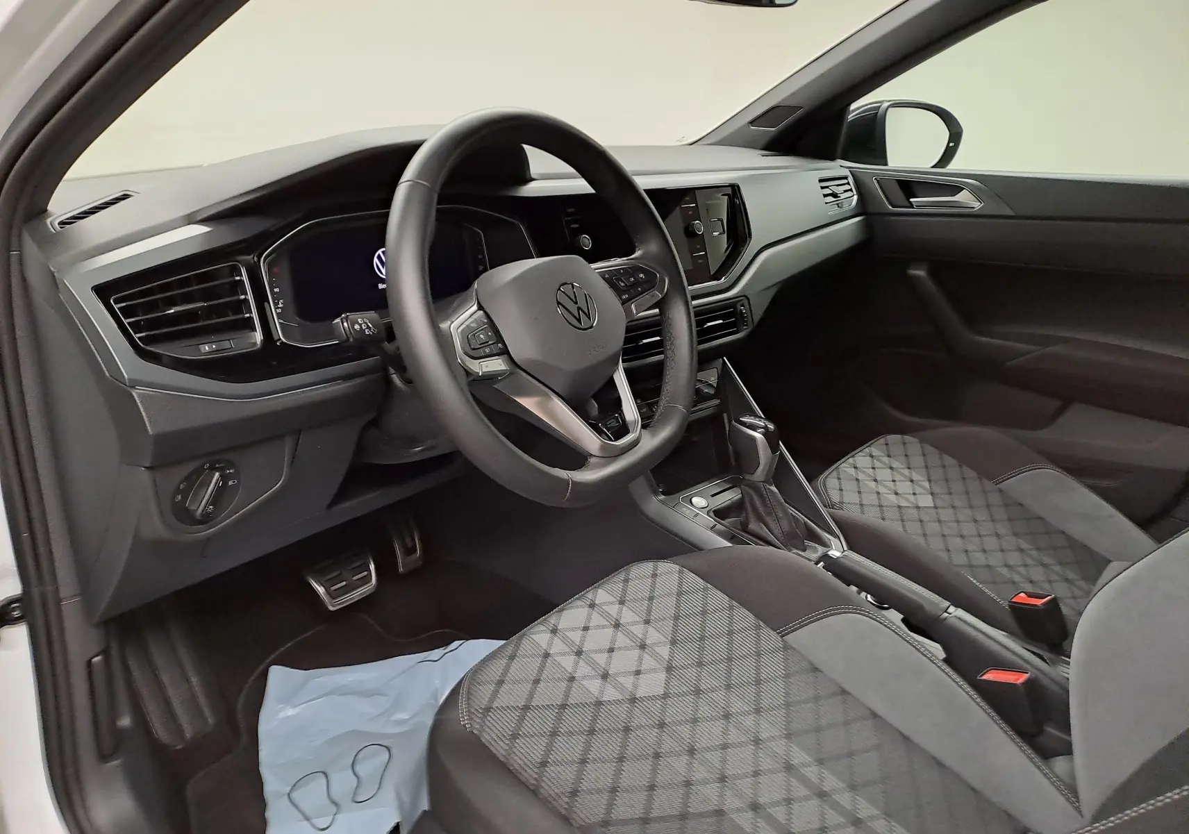 Vue intérieure côté conducteur du Volkswagen Taigo 1.5 TSI 150 DSG7 R-Line Edition avec sièges tissu à motif losanges.