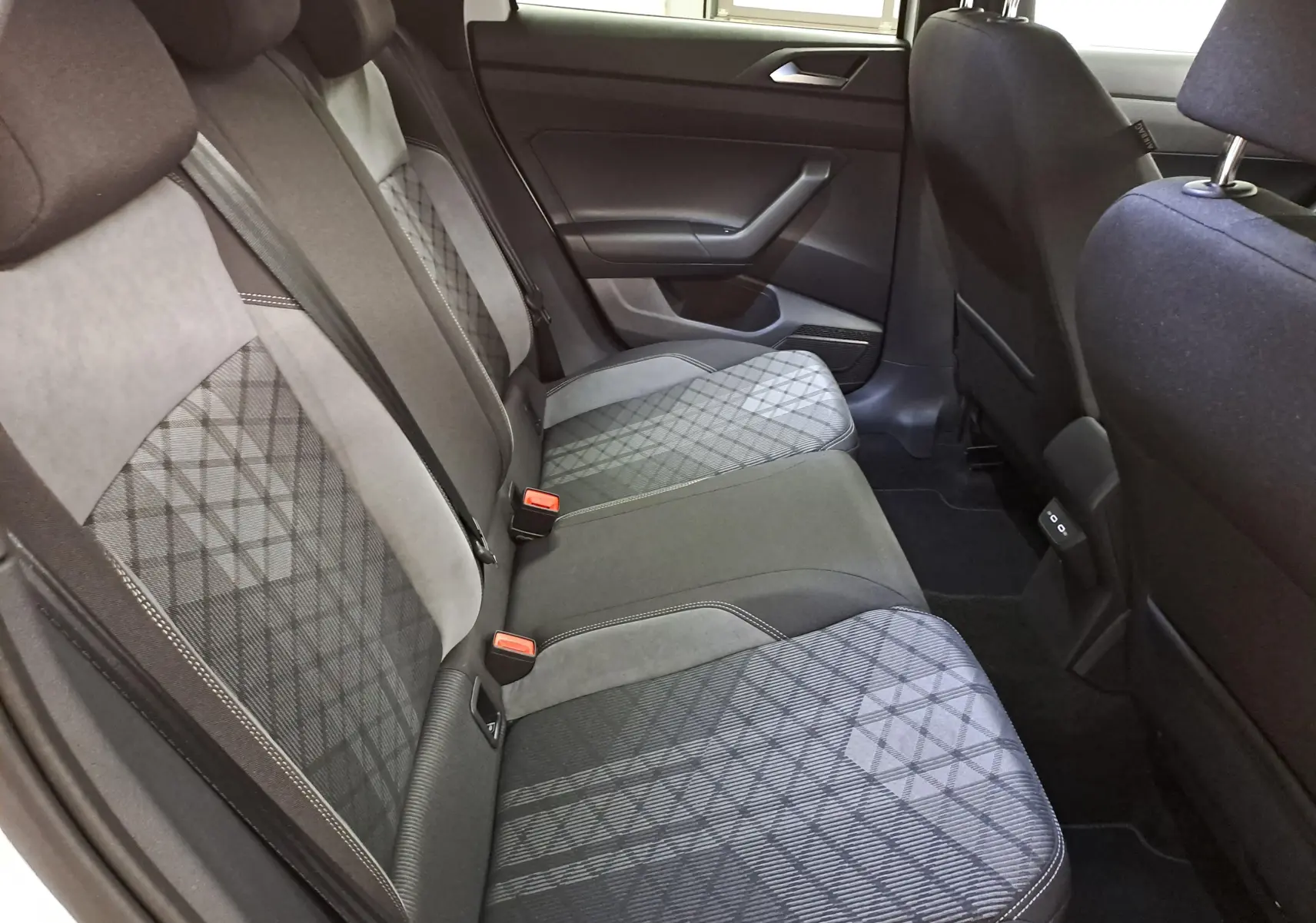 Vue intérieure sur les sièges arrière en tissu gris à motifs géométriques du Volkswagen Taigo 2025, côté droit.