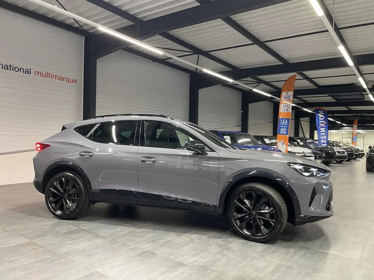 Vue de profil droit du CUPRA Formentor gris Graphene avec jantes alliage noires en showroom lumineux.