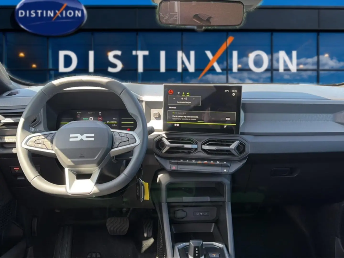 Vue intérieure avant du tableau de bord du Dacia Duster 2026 avec volant multifonction et écran tactile central.