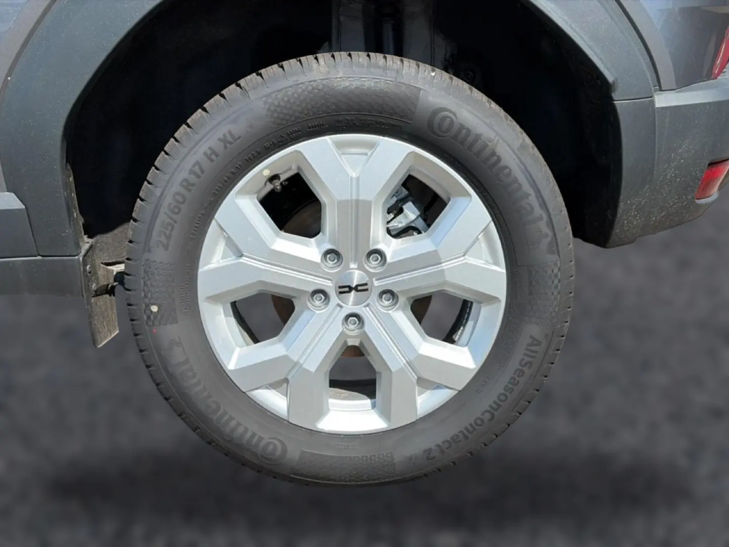 Gros plan sur la roue arrière droite du Dacia Duster gris schiste, avec jante alu à design hexagonal.