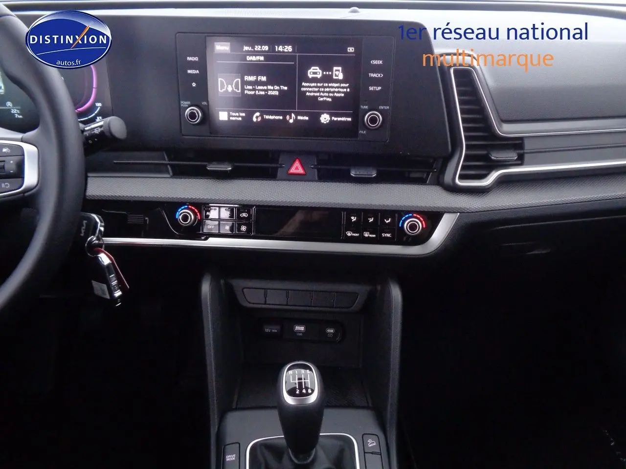 Vue intérieure centrée sur la console centrale du Kia Sportage 2022, avec boîte manuelle et écran tactile multifonction.