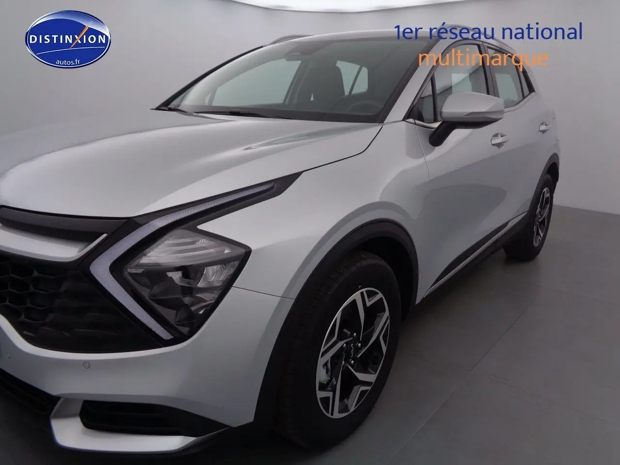 KIA SPORTAGE gris acier métal vu de 3/4 avant droit, mettant en valeur ses phares LED et jantes bicolores.