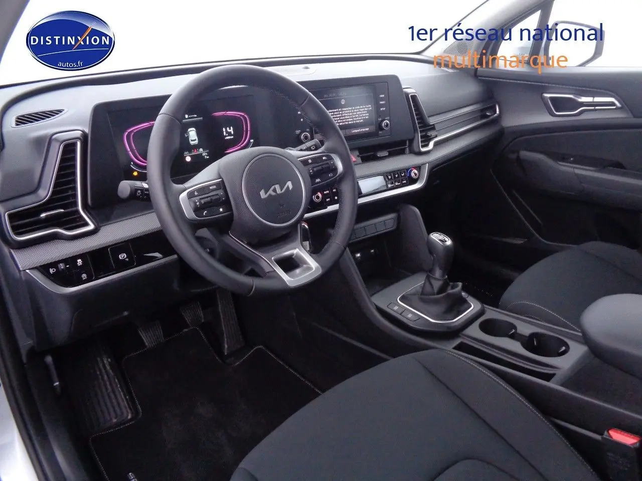 Vue intérieure côté conducteur du Kia Sportage 2022, volant multifonction et boîte manuelle dans un habitacle noir moderne.