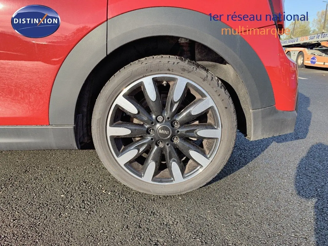 Gros plan sur la roue arrière droite d'une MINI rouge chili avec jante alliage noire et argentée.