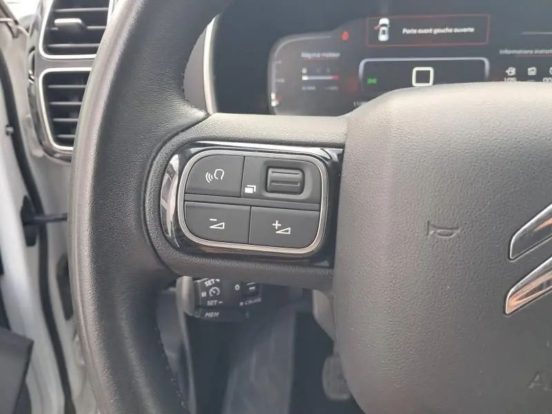 Gros plan sur les commandes gauche du volant d'un Citroën C5 Aircross blanc 2019, version HDi 130 Shine.