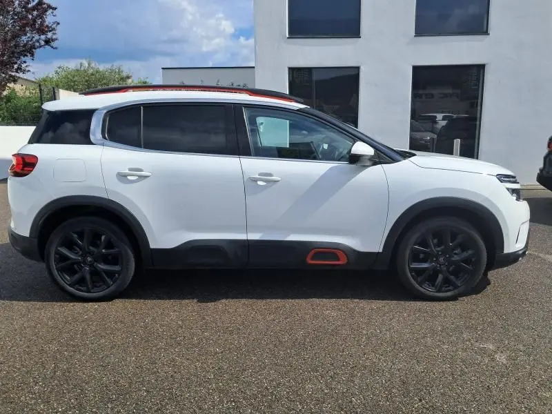 Profil côté droit du Citroën C5 Aircross blanc 2019 avec jantes noires et détails orange sur bas de caisse.