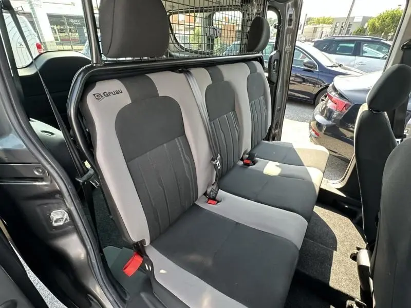 Vue intérieure côté droit des sièges arrière gris foncé et clair du Fiat Doblo Cargo 2021 avec séparation métallique de cabine