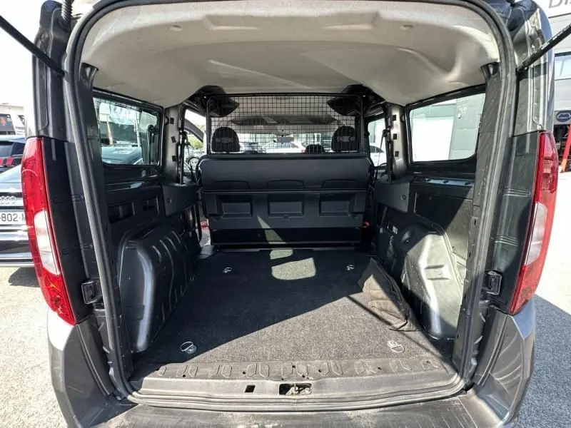 Vue arrière ouverte du FIAT Doblo Cargo gris foncé 2021, montrant l'espace de chargement vide et la cloison métallique intérieure.