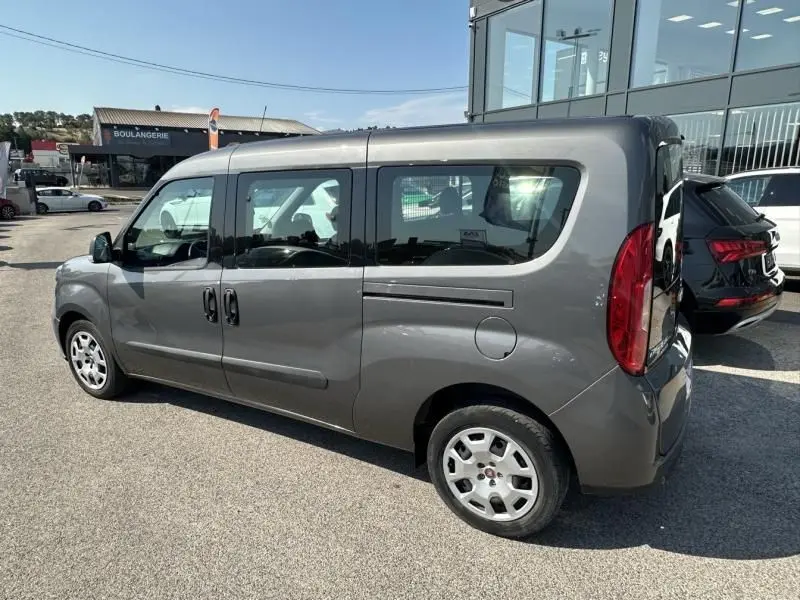 Fiat Doblo Cargo Maxi gris foncé vu de profil côté gauche, avec portes coulissantes et vitres latérales.