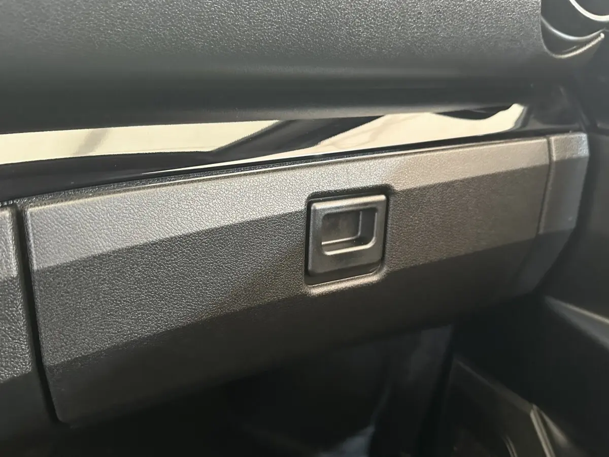 Gros plan sur la boîte à gants noire à l'intérieur de l'AIXAM AMBITION 0.5 CITY SPORT 2026.