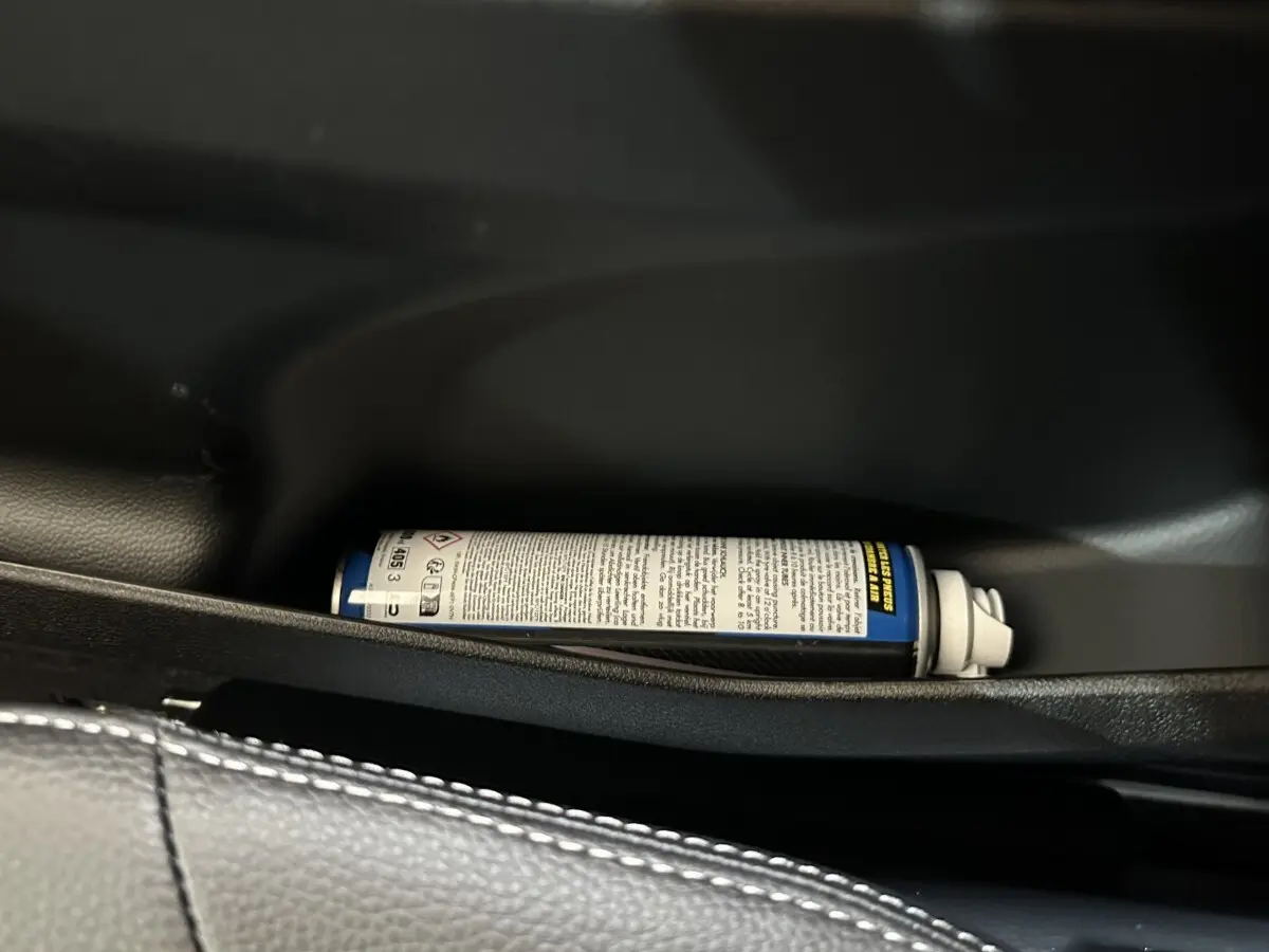 Gros plan sur le rangement intérieur côté conducteur de l'AIXAM AMBITION 0.5 CITY SPORT 2026 avec un spray posé.