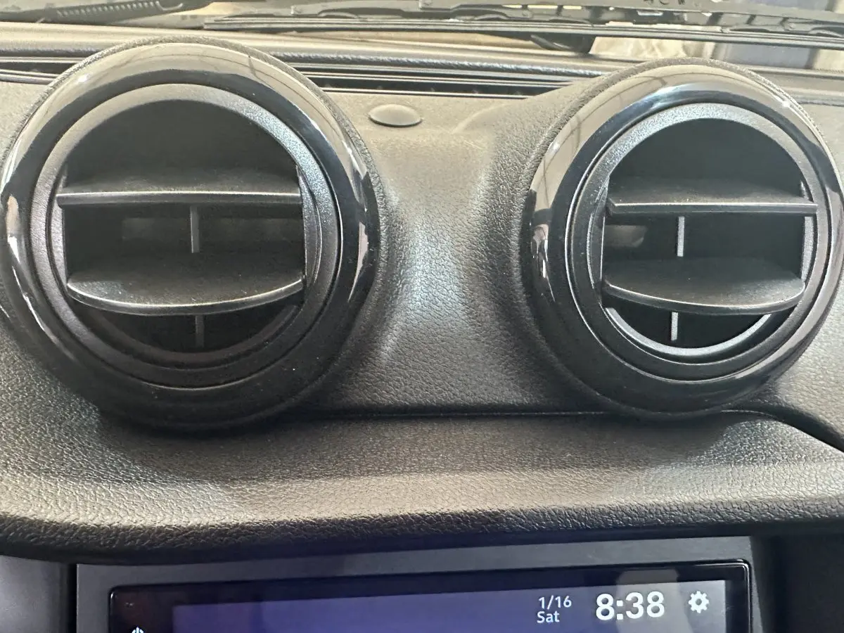 Vue rapprochée des aérateurs ronds noirs du tableau de bord de l'AIXAM AMBITION 0.5 CITY SPORT rouge, année 2026.