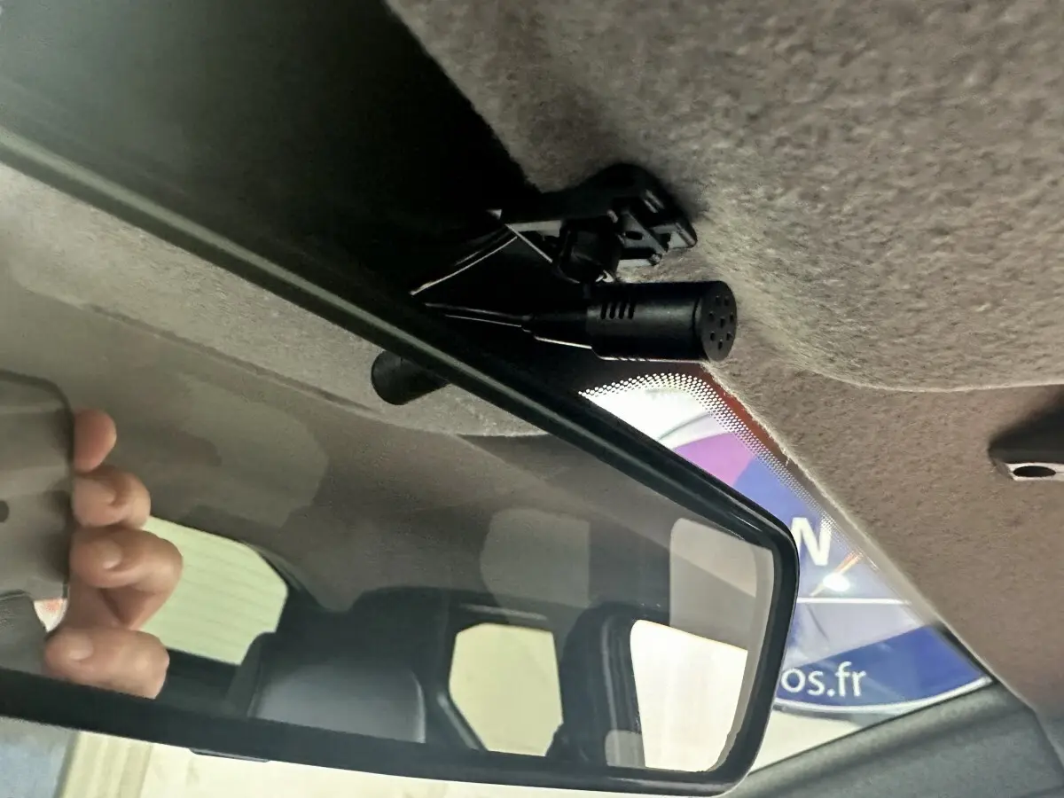 Vue intérieure du rétroviseur central d'une Aixam Ambition 0.5 City Sport rouge, avec micro fixé au plafond.