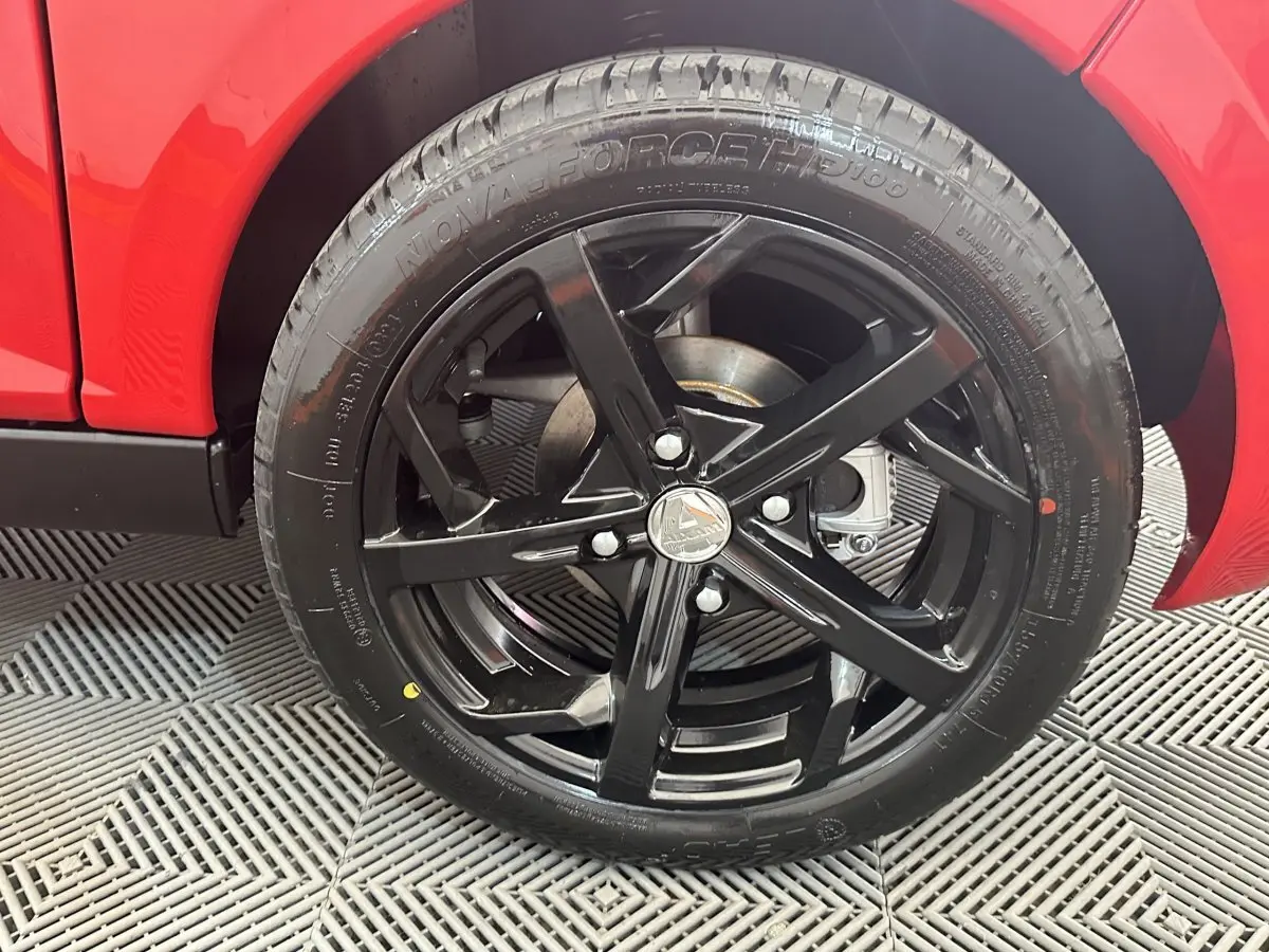 Gros plan sur la roue arrière droite noire brillante de l'AIXAM AMBITION 0.5 CITY SPORT rouge 2026.