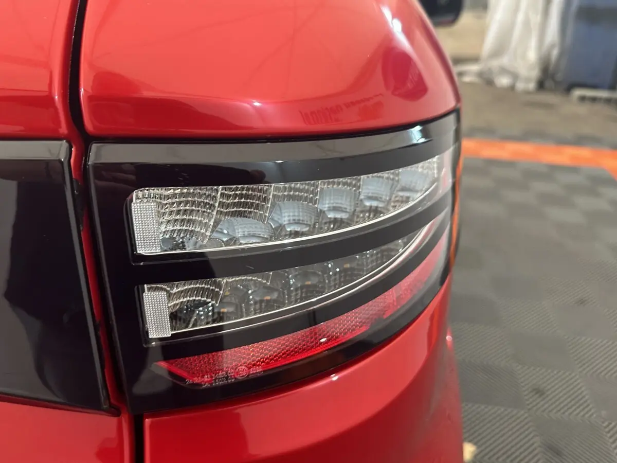 Gros plan sur le feu arrière droit rouge de l'AIXAM AMBITION 0.5 CITY SPORT 2026 avec détails lumineux nets.