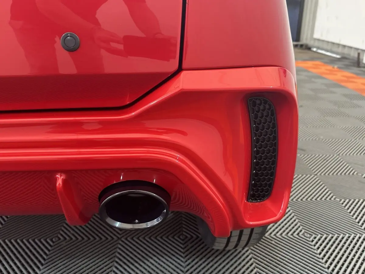 Gros plan sur l'arrière droit rouge de l'AIXAM AMBITION 0.5 CITY SPORT avec sortie d'échappement et diffuseur.