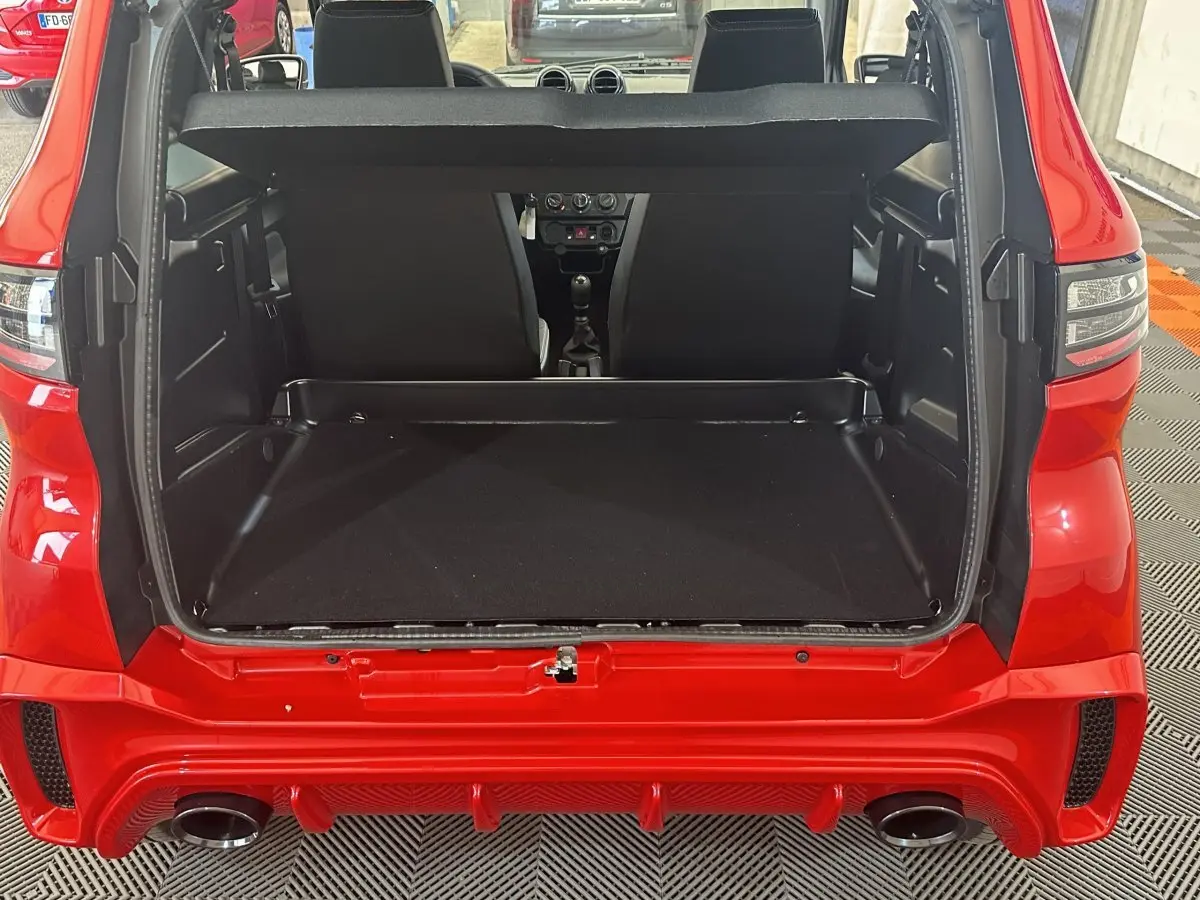 Vue arrière ouverte du coffre de l'AIXAM AMBITION 0.5 CITY SPORT rouge 2026 avec intérieur noir et banquette avant visible.