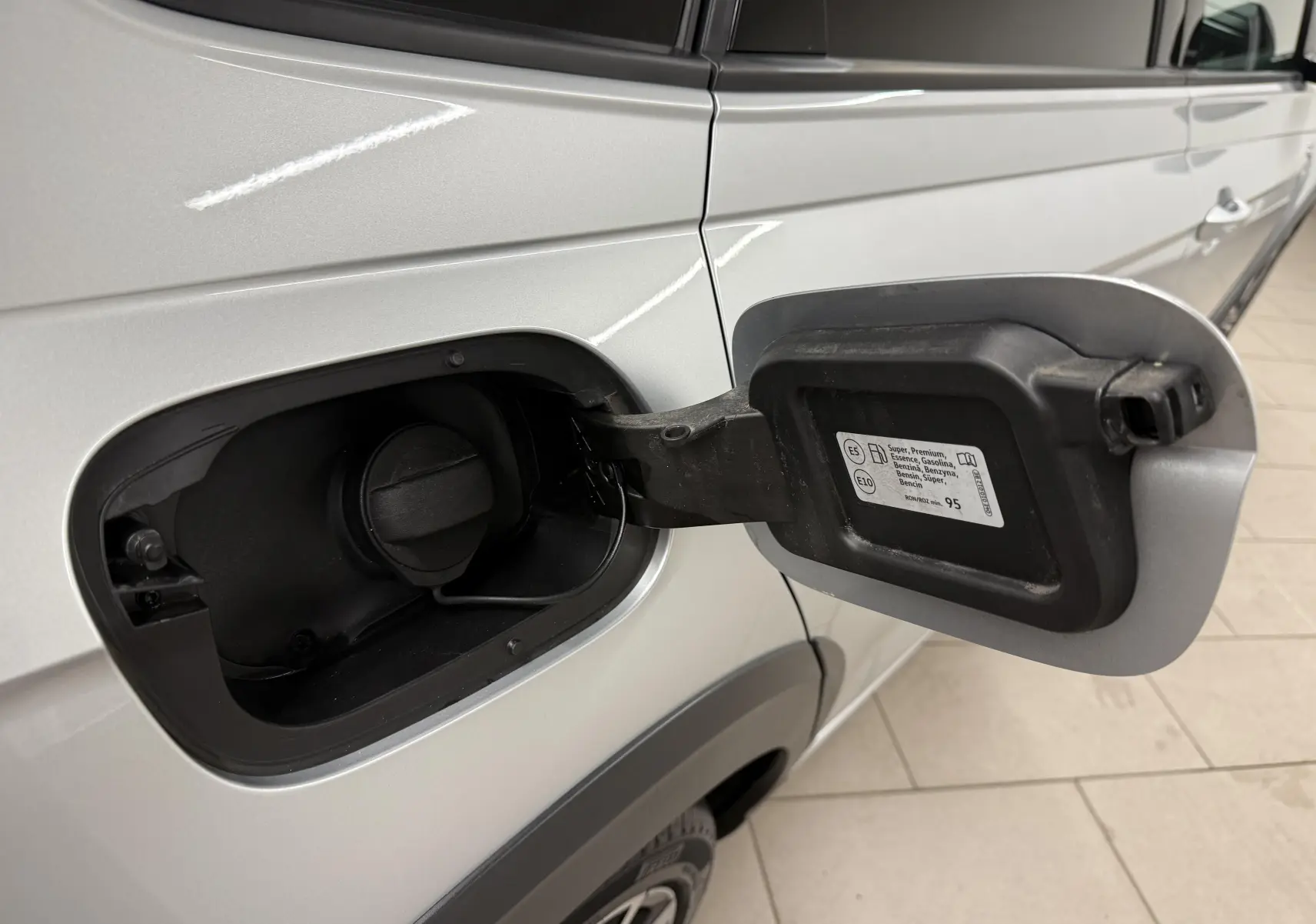Vue rapprochée du volet de remplissage carburant ouvert côté gauche d’un Volkswagen Taigo argent métallisé avec toit noir.