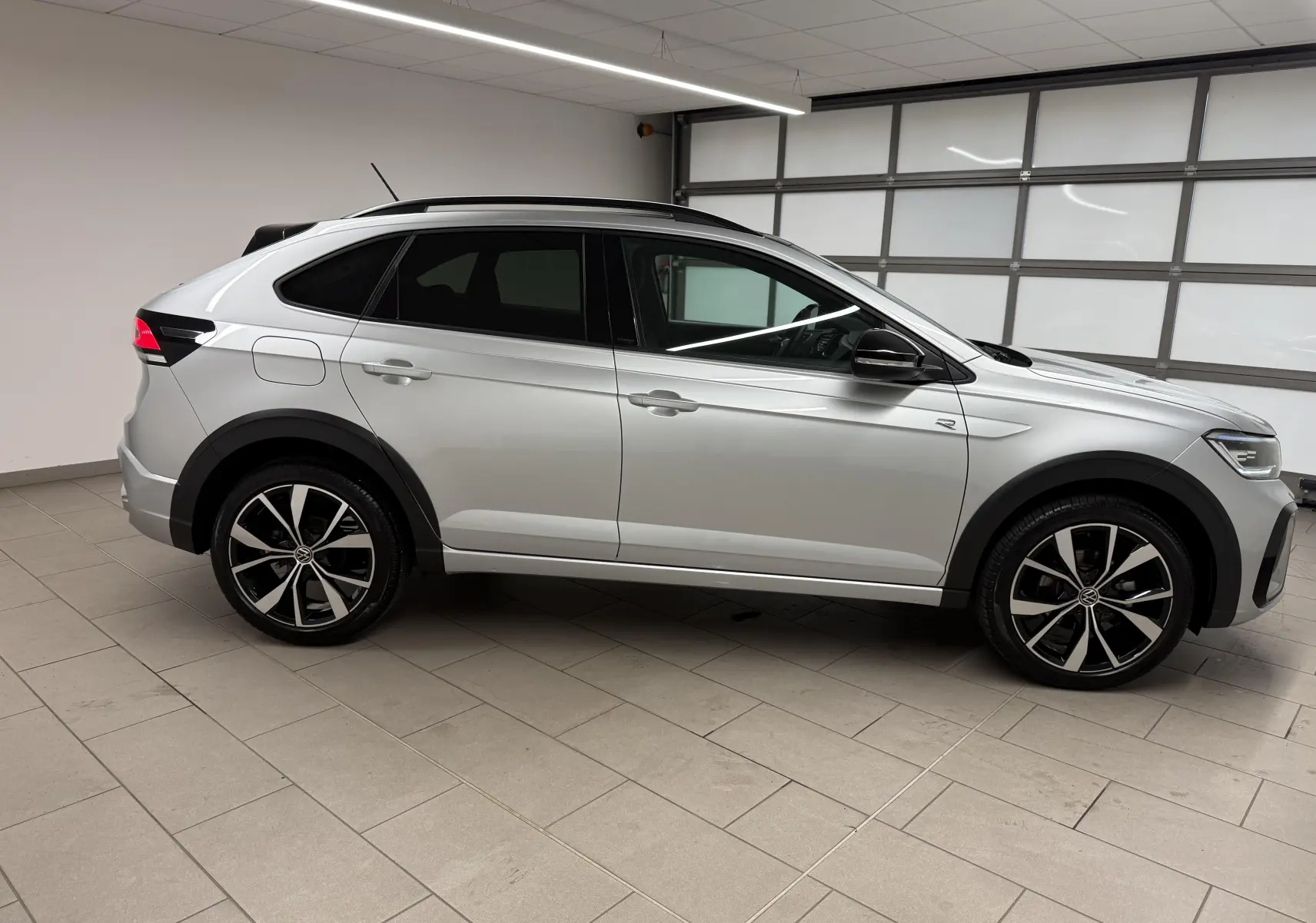 Volkswagen Taigo 2025 en profil côté gauche, peinture argent métallisée avec toit noir et jantes alliage 18 pouces.